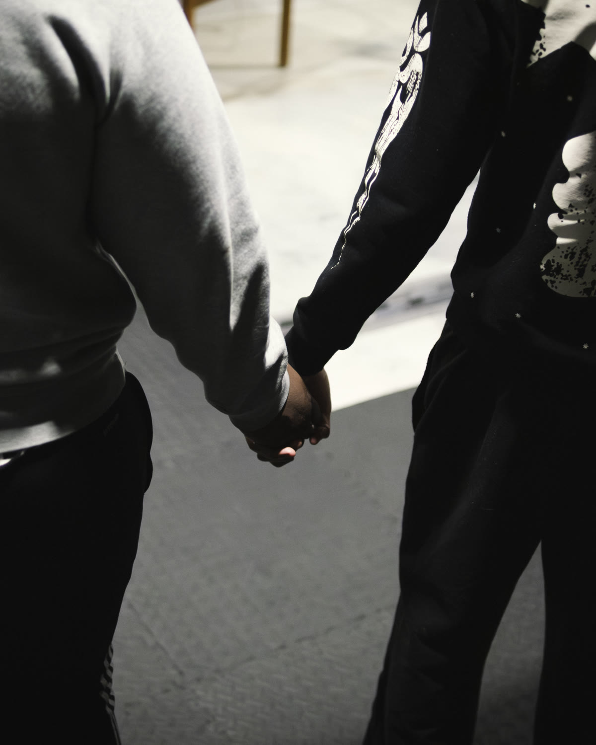 Two young people holding hands during a prayer circle at a LIGHT Joy Night